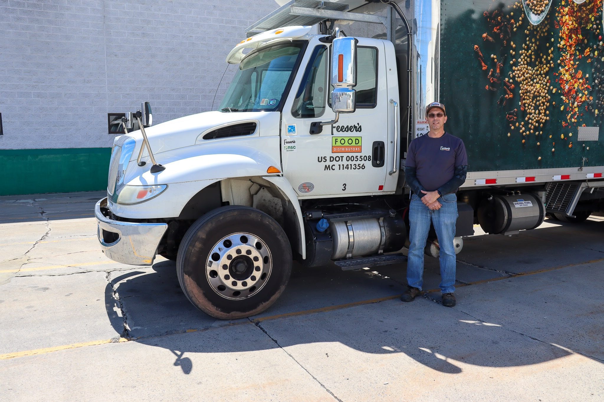 a man stands in front of a Feeser's delivery box truck