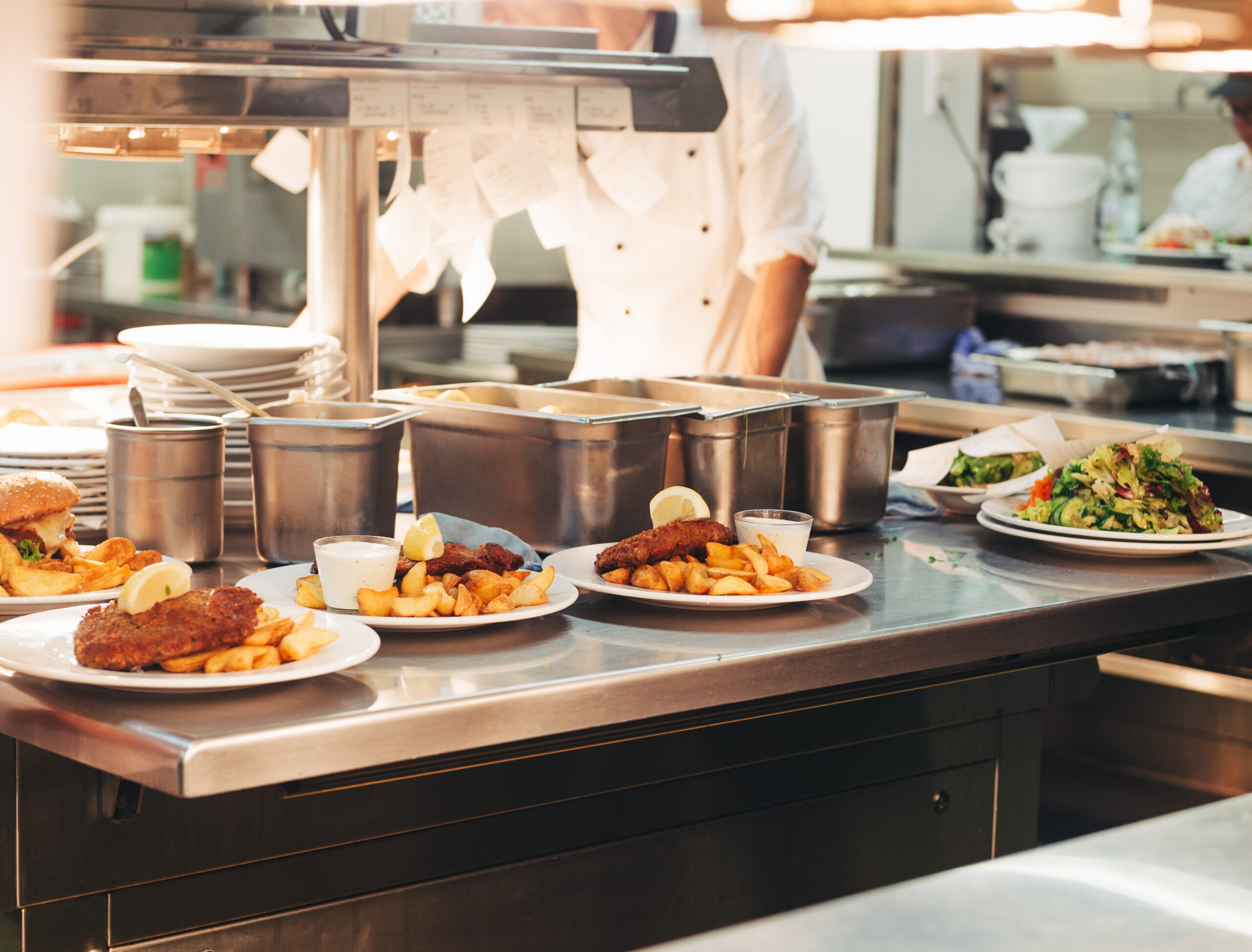 several plates of food on a counter with a chef in the background