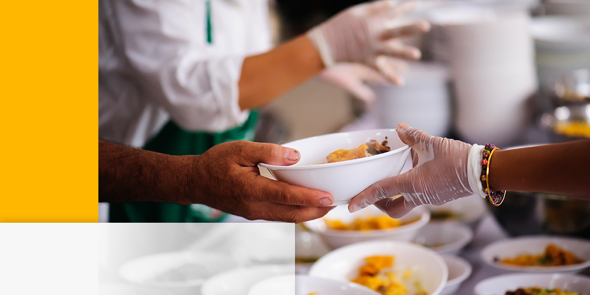 a person wearing gloves is handing a bowl of food to another person