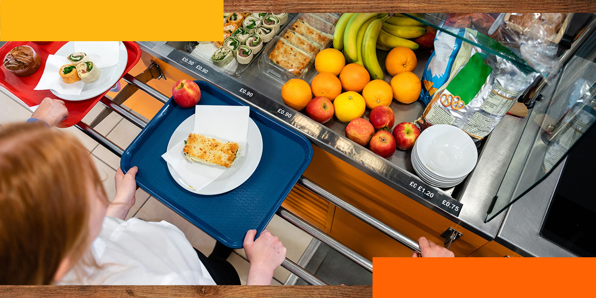 a person is holding a tray with food on it in a cafeteria line